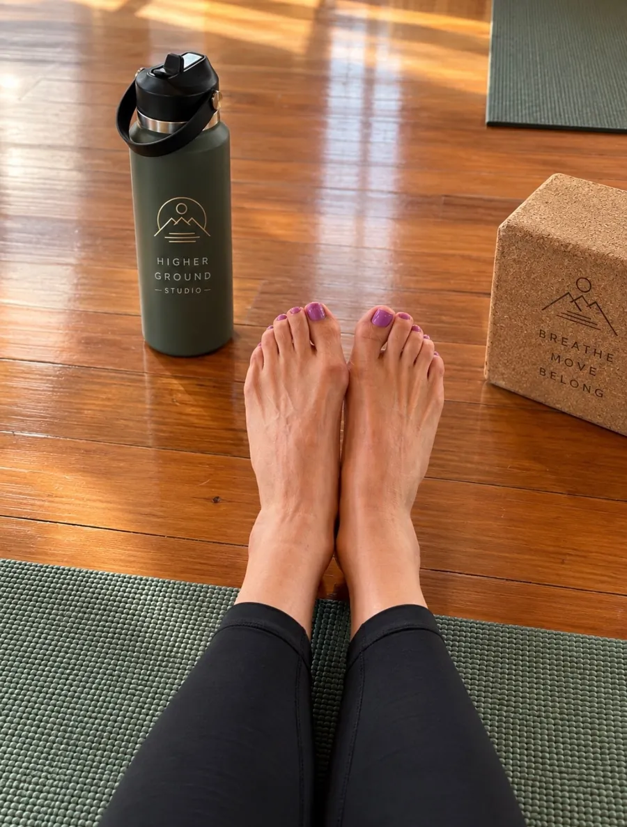 Higher Ground Studio water bottle and a cork block reading breathe, move, belong beside a green mat