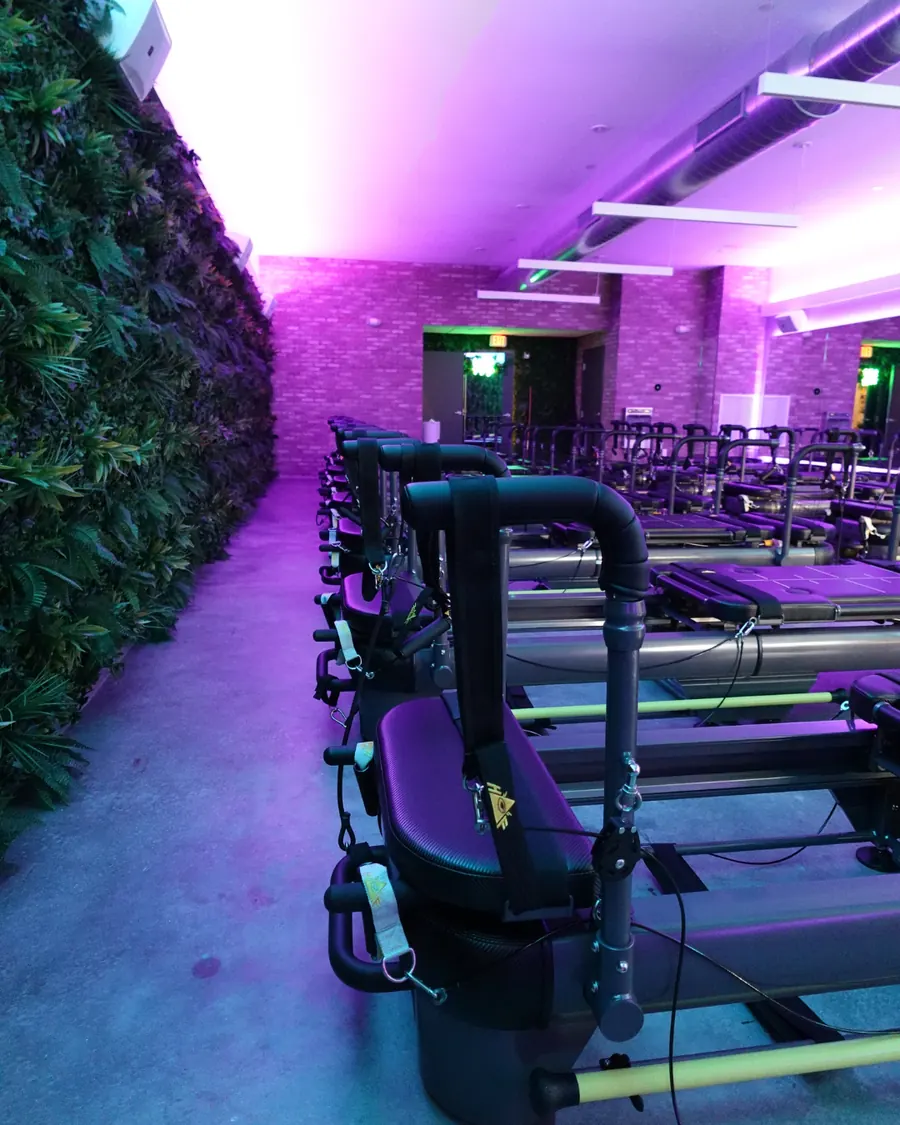 Machines lined up along a brick wall lit in teal and purple